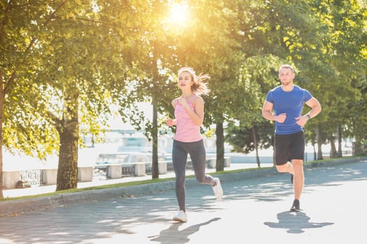 The sporty woman and man jogging at park in sunrise light at morning