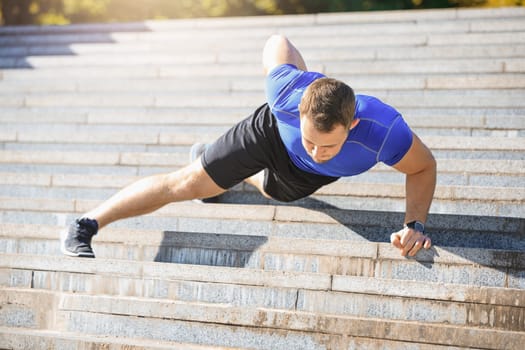 Fit fitness man doing exercises outdoors at park. The man doing exercises. The male sports model jumping outdoor in summer.