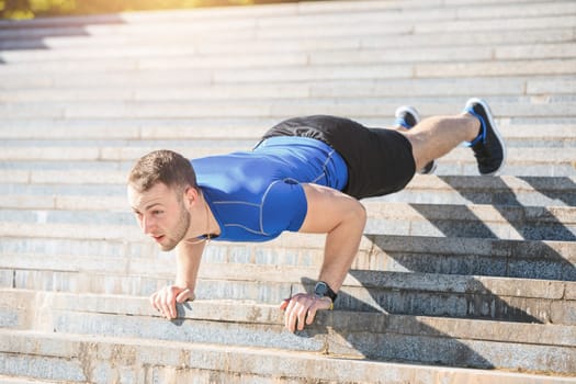 Fit fitness man doing exercises outdoors at park. The man doing exercises. The male sports model jumping outdoor in summer.