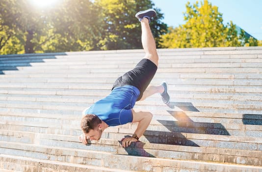 Fit fitness man doing exercises outdoors at park. The man doing exercises. The male sports model jumping outdoor in summer.