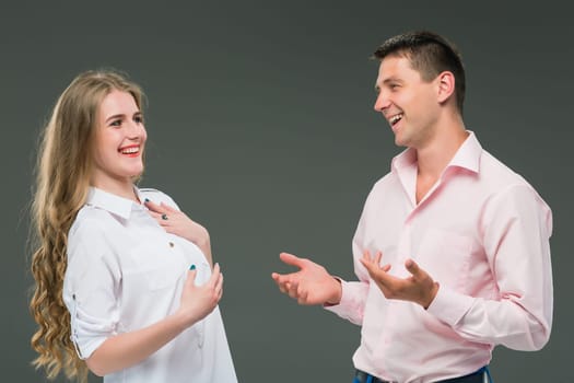 Portrait of a young smiling couple standing against gray studio background