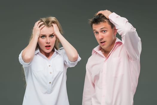 The young couple with different emotions during conflict on gray background