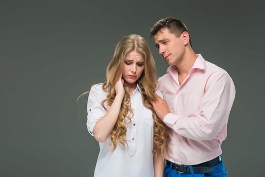 The young couple with different emotions during conflict on gray background