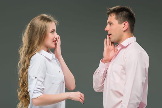 Portrait of a young couple standing against gray studio background