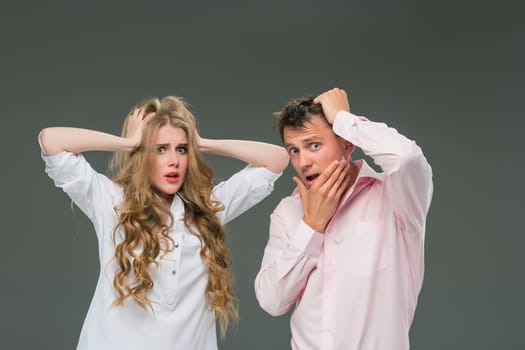 Portrait of a young couple standing against gray studio background