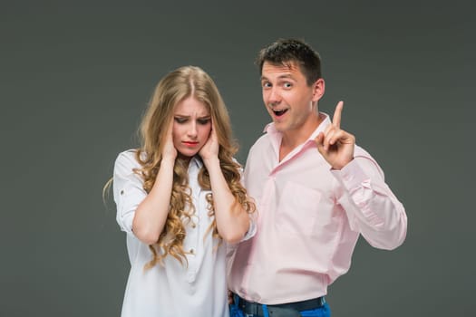 The young couple with different emotions during conflict on gray background