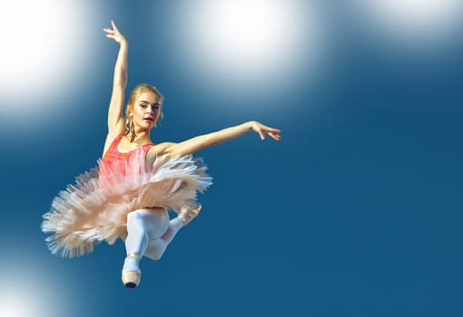Beautiful female ballet dancer on a grey background. Ballerina is wearing pink tutu and pointe shoes