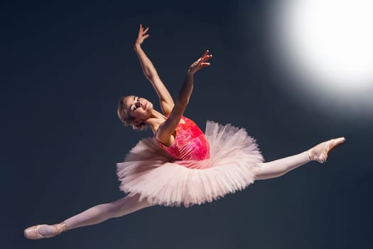 Beautiful female ballet dancer on a dark background. Ballerina is wearing pink tutu and pointe shoes