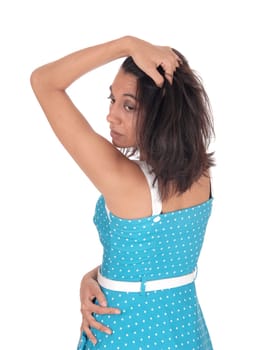 A serious young woman standing waist up in a blue dress from the back.with one hand on her head, isolated for white background..