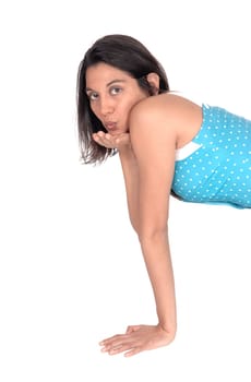 A beautiful young woman in a blue dress kneeling isolated for white.background and blowing a kiss..