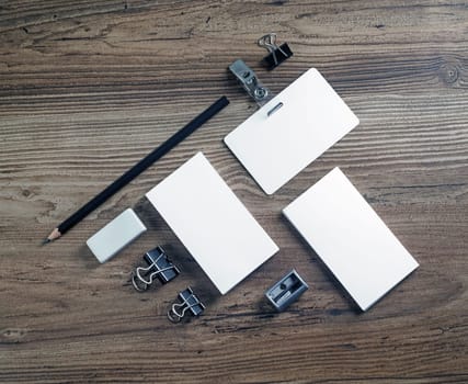 Photo of blank stationery set on wood table background. Branding mockup. Business cards, pencil, eraser, badge and sharpener. Responsive design template. Top view.