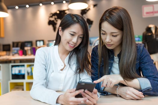 Friends looking at cellphone in coffee shop