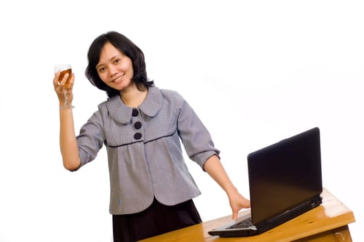Beautiful asian business woman celebrating her success with wine in front of her computer
