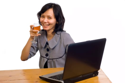 Beautiful asian business woman celebrating her success with wine in front of her computer