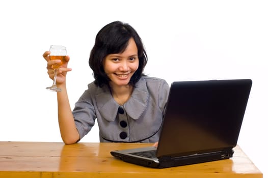 Beautiful asian business woman celebrating her success with wine in front of her computer