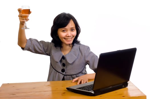 Beautiful asian business woman celebrating her success with wine in front of her computer