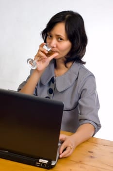 Beautiful asian business woman celebrating her success with wine in front of her computer