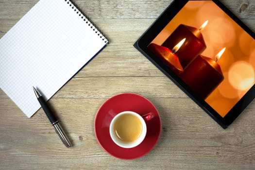 Tablet with picture of candles with flame and bokeh as top view with block and coffee