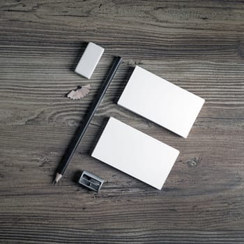 Business cards, pencil, eraser and sharpener on wood background. Mockup for your design. Blank stationery set. Responsive design template. Top view.