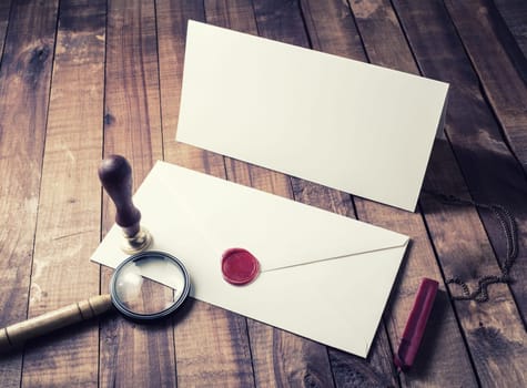 Photo of vintage postal accessories. Stationery set. Blank envelope, postcard, magnifier, seal, stamp on wooden table background.