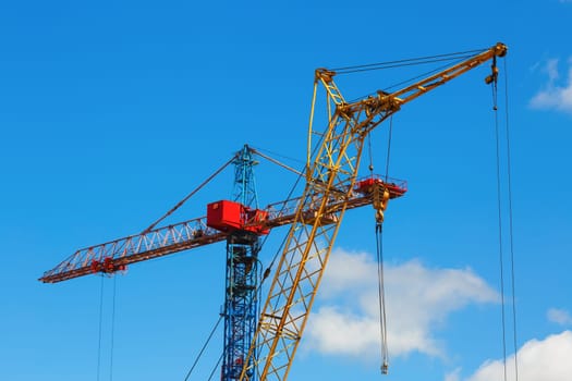 Tower crane and mobile construction crane against blue sky background