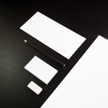 Photo of blank stationery set on black wooden table background. Corporate identity template for ID. Responsive design mockup.