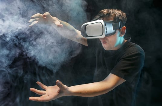 The man with glasses of virtual reality. Future technology concept. Black studio smoky background