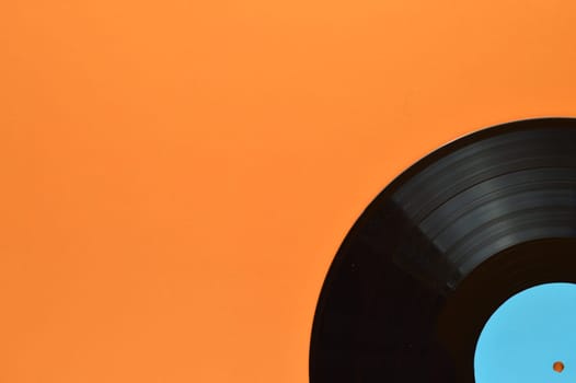 old black vinyl record with blank cyan label in the edge of orange background