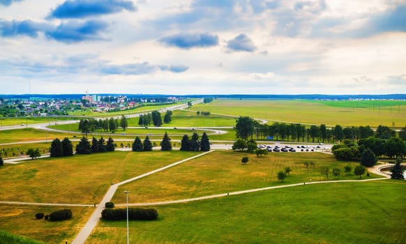 Summer countryside landscape. Green fields, meadows, trees, roads, houses and blue sky with clouds. Minsk region, Belarus