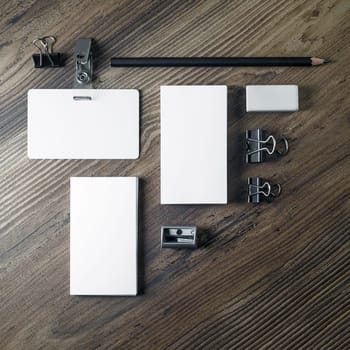 Photo of blank stationery. Template for placing your design. Business cards, pencil, eraser, badge and sharpener on wood table background. Top view.