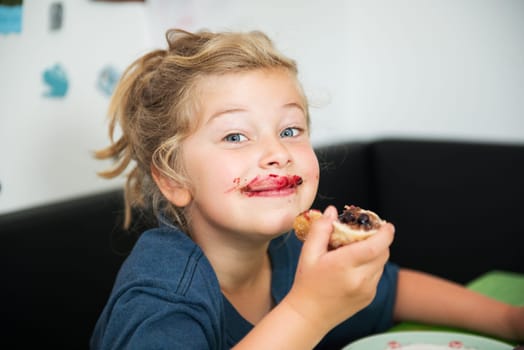 funny girl eating bread roll with dark marmelade