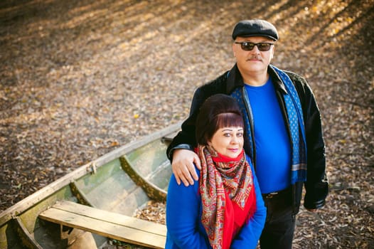 adult couple walking in autumn park. husband and wife walking outdoors in autumn last days, man with a mustache wearing sunglasses