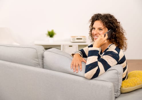 Beautiful woman sitting on the sofa and making a phone call