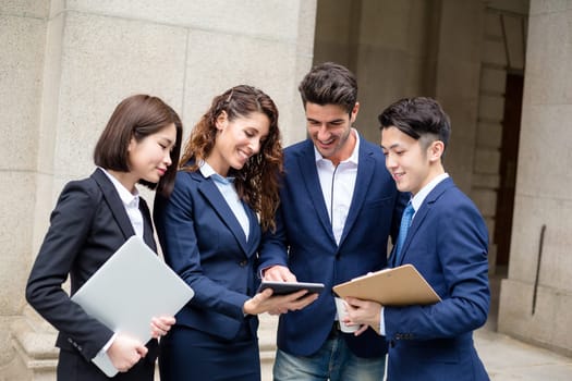 Group of business people discuss something on tablet
