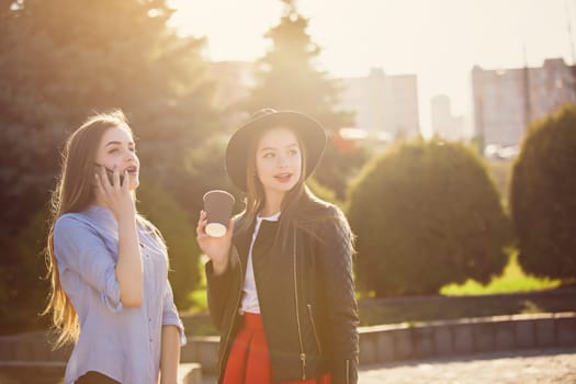 Two girls walking with shopping bags on city streets at sunny day