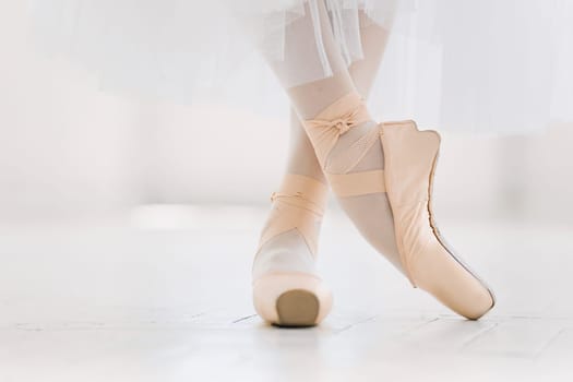 Young ballerina dancing, closeup on legs and shoes, standing in pointe position.