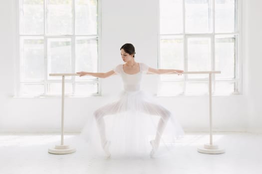Young and incredibly beautiful ballerina is posing and dancing in a white studio full of light.