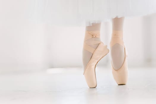 Young ballerina dancing, closeup on legs and shoes, standing in pointe position.