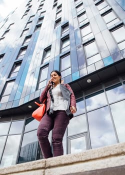 Businesswoman is leaving work while talking to someone on her mobile phone.