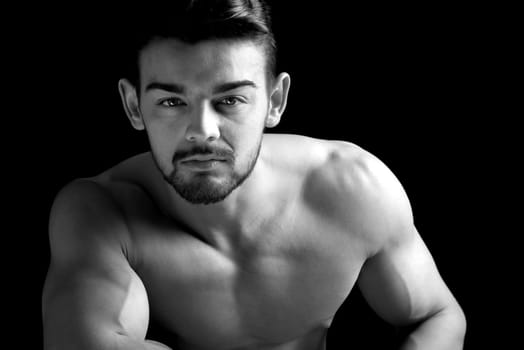 Handsome young man, shirtless, with great body posing over a black background