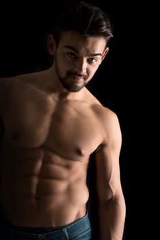 Handsome young man, shirtless, with great body posing over a black background