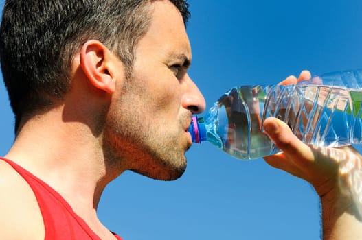 Man is drinking water against blue sky