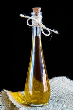 Glass bottle of extra virgin olive oil on a black background