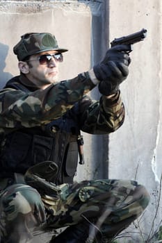 The soldier is shooting with the gun.
