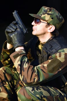 The soldier is holding a handgun, profile view.
