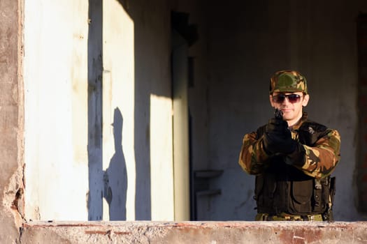 The soldier is shooting with the gun.