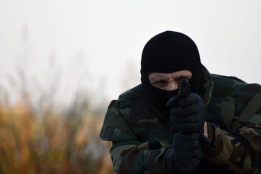 The soldier is shooting with gun outdoor.