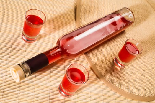 Alcohol bottle and glasses with red alcohol drink.