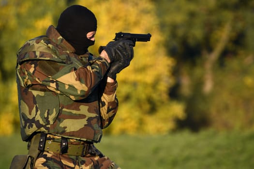 The soldier shoots with gun in nature.