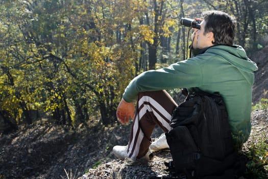 The mountaineer is looking away the nature with his binoculars.